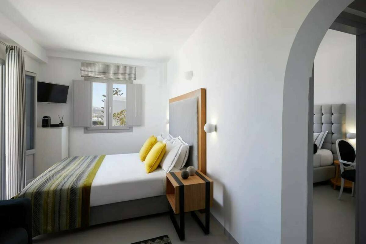 Un dormitorio moderno con cama, mesita de noche y televisión montada en la pared.