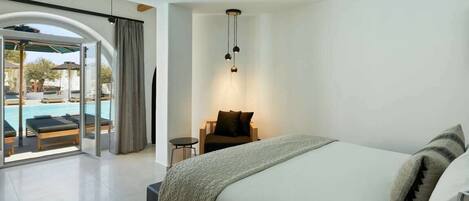 A modern hotel room with a large bed, a small desk, and a view of a pool area.