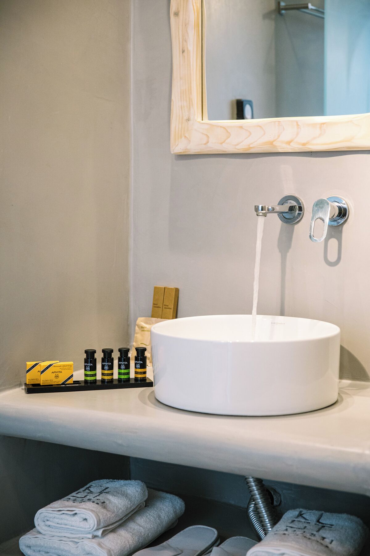 Een badkamer met een wit wastafel, een spiegel en toiletartikelen op het aanrecht.