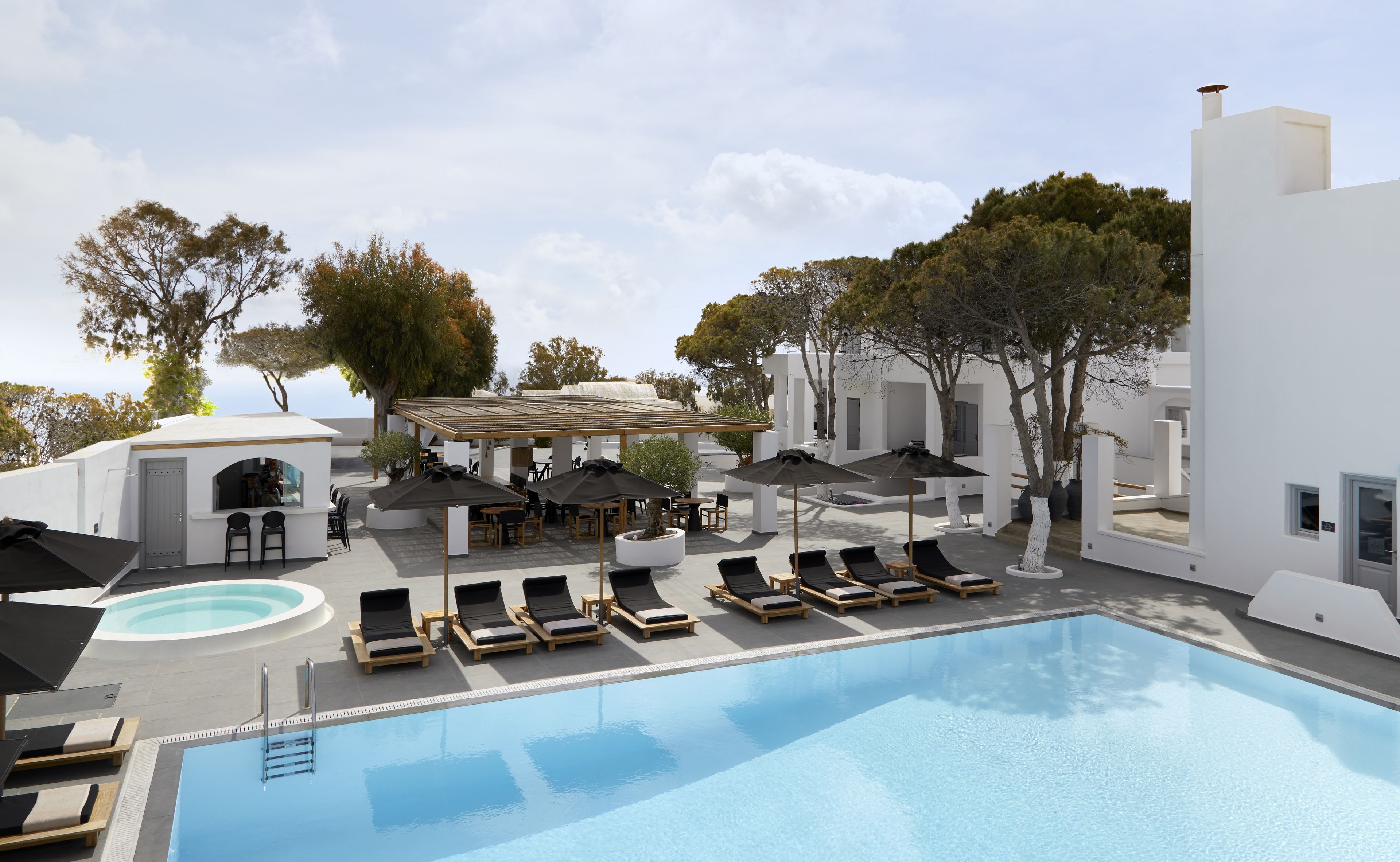 A pool area with lounge chairs, umbrellas, and a covered seating area.