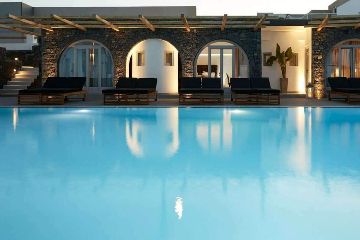 Una piscina con sillas de descanso y un edificio de piedra con arcos.