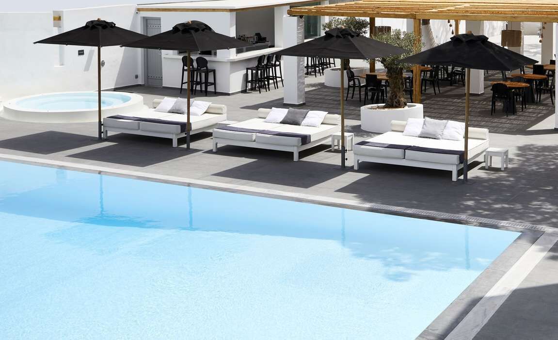 Ein Poolbereich mit Liegestühlen, Sonnenschirmen und einer Bar.
