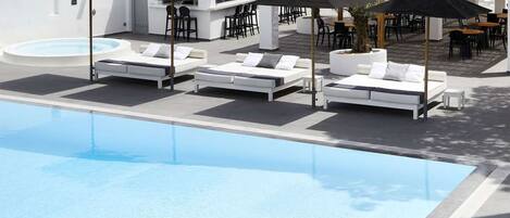 Ein Poolbereich mit Liegestühlen, Sonnenschirmen und einer Bar.