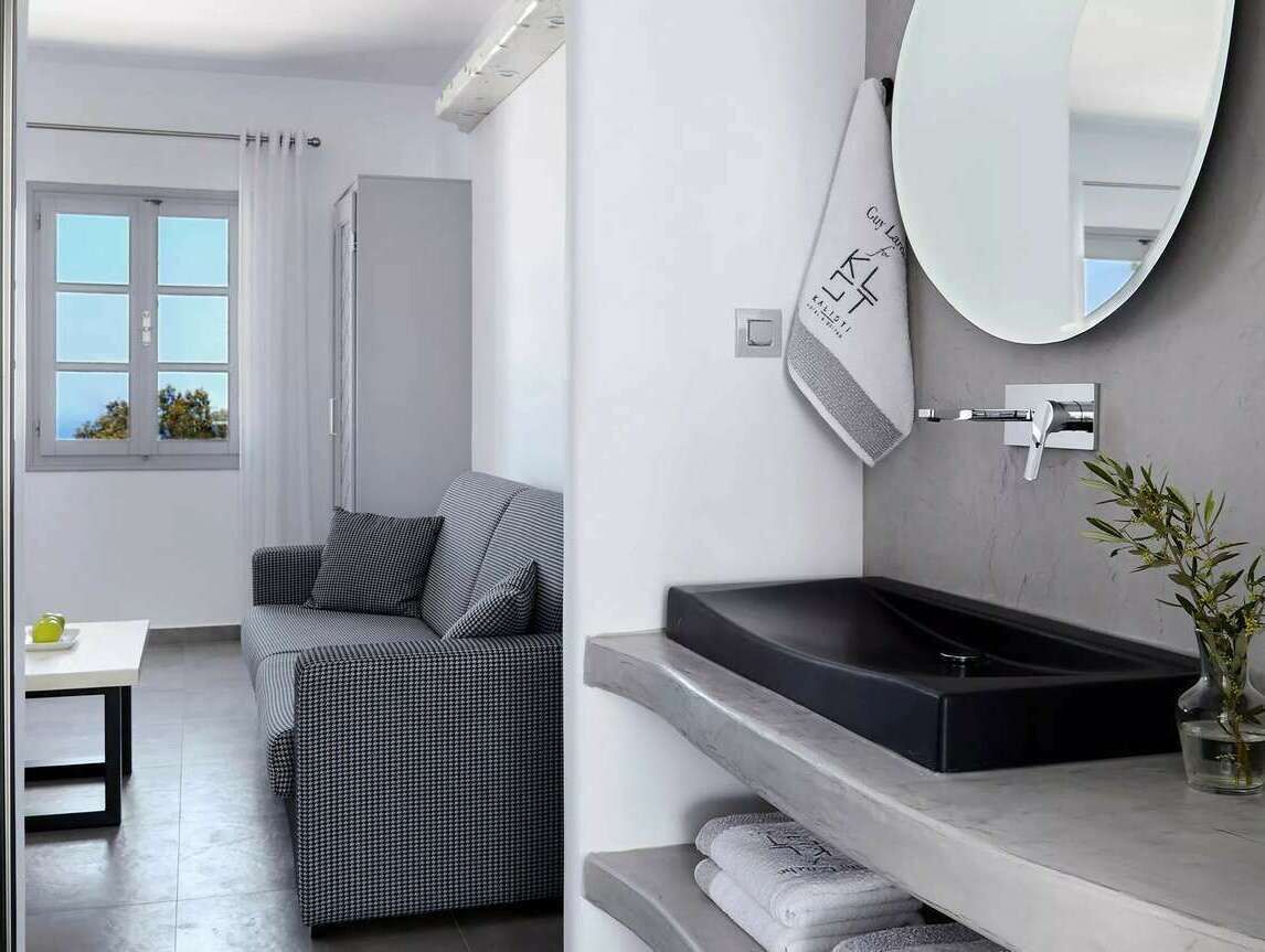 Un baño moderno con un lavabo negro, un espejo grande y un perchero para toallas.
