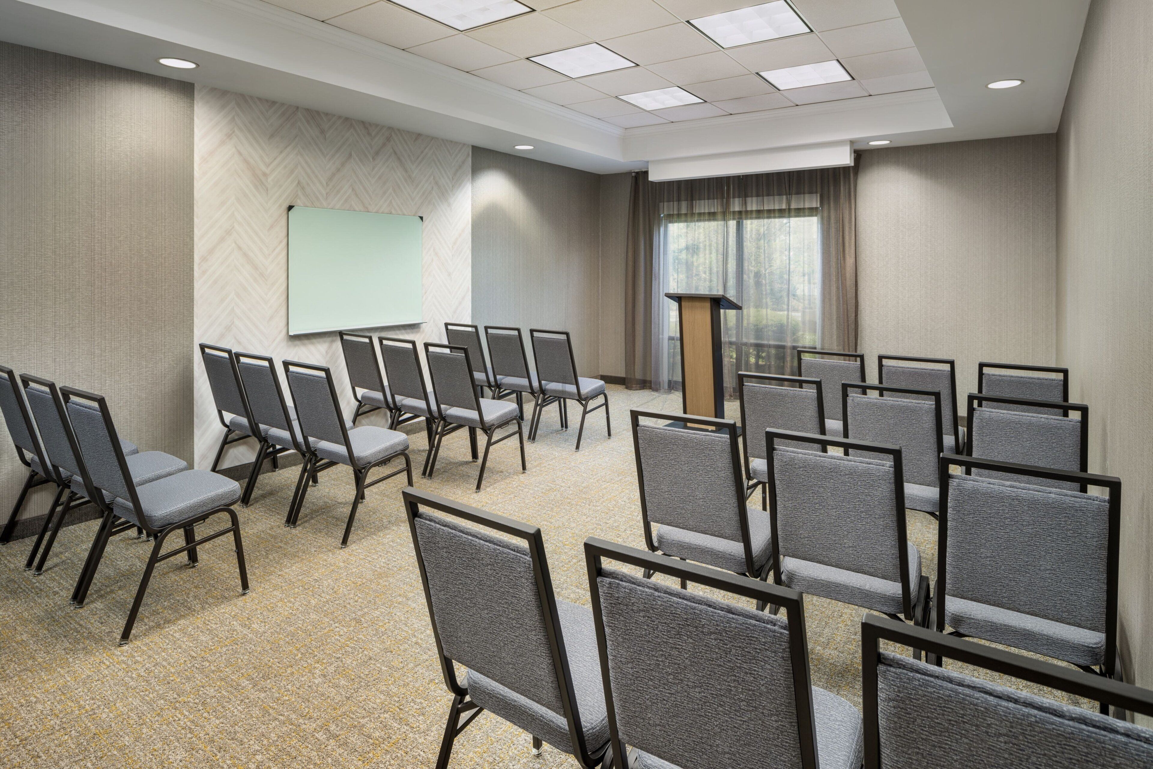 A conference room with rows of chairs, a whiteboard, and a podium.