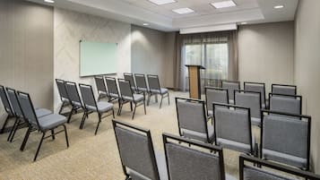 A conference room with rows of chairs, a whiteboard, and a podium.