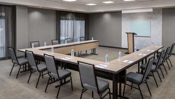 A conference room with a long table, chairs, water bottles, and a presentation screen.