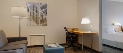 Une chambre d’hôtel équipée d’un canapé, d’un bureau, d’une chaise, d’une table de chevet, d’une lampe et d’un lit.