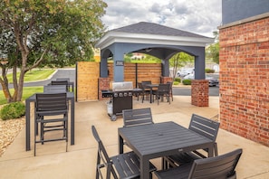 An outdoor patio with a covered seating area, a grill, and a table with chairs. - Candlewood Suites St Robert by IHG (St. Robert)