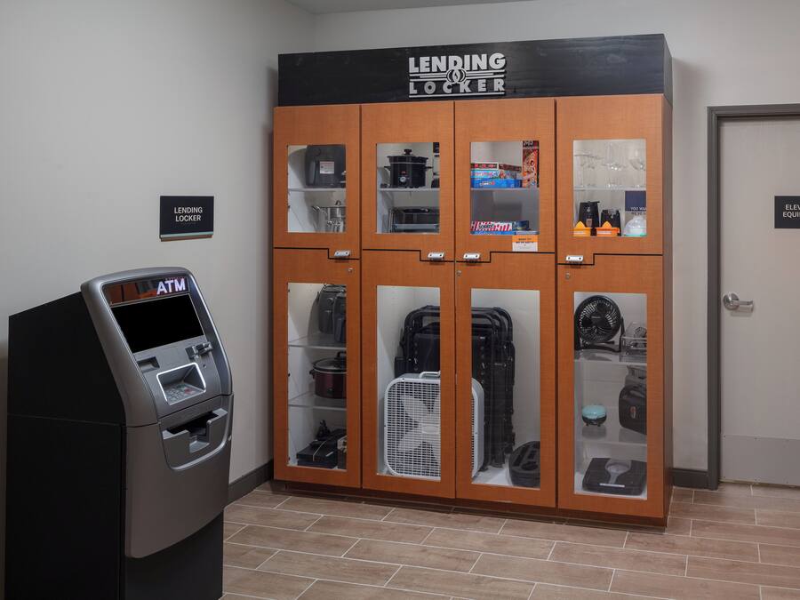 A lending locker with a sign above it, an ATM, and a door labeled "Elevator Equipment".