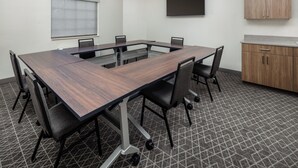 A conference room with a long table, chairs, a television, and a cabinet. - Candlewood Suites St Robert by IHG (St. Robert)