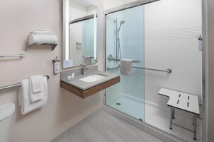 A modern bathroom with a glass-enclosed shower, a sink with a wooden vanity, and a towel rack.