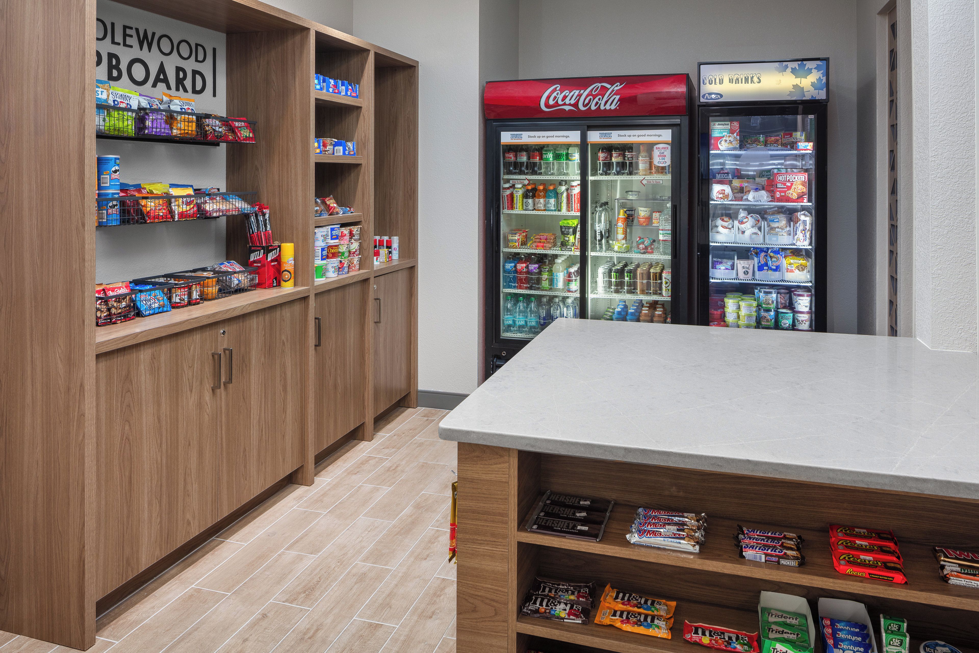 A snack bar area with shelves stocked with various snacks and a Coca-Cola refrigerator.