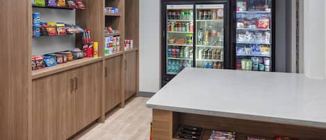 A snack bar area with shelves stocked with various snacks and a Coca-Cola refrigerator.