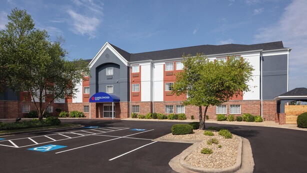 A hotel with a parking lot, marked handicapped spaces, and a sign for Candlewood Suites. - Candlewood Suites St Robert by IHG (St. Robert)