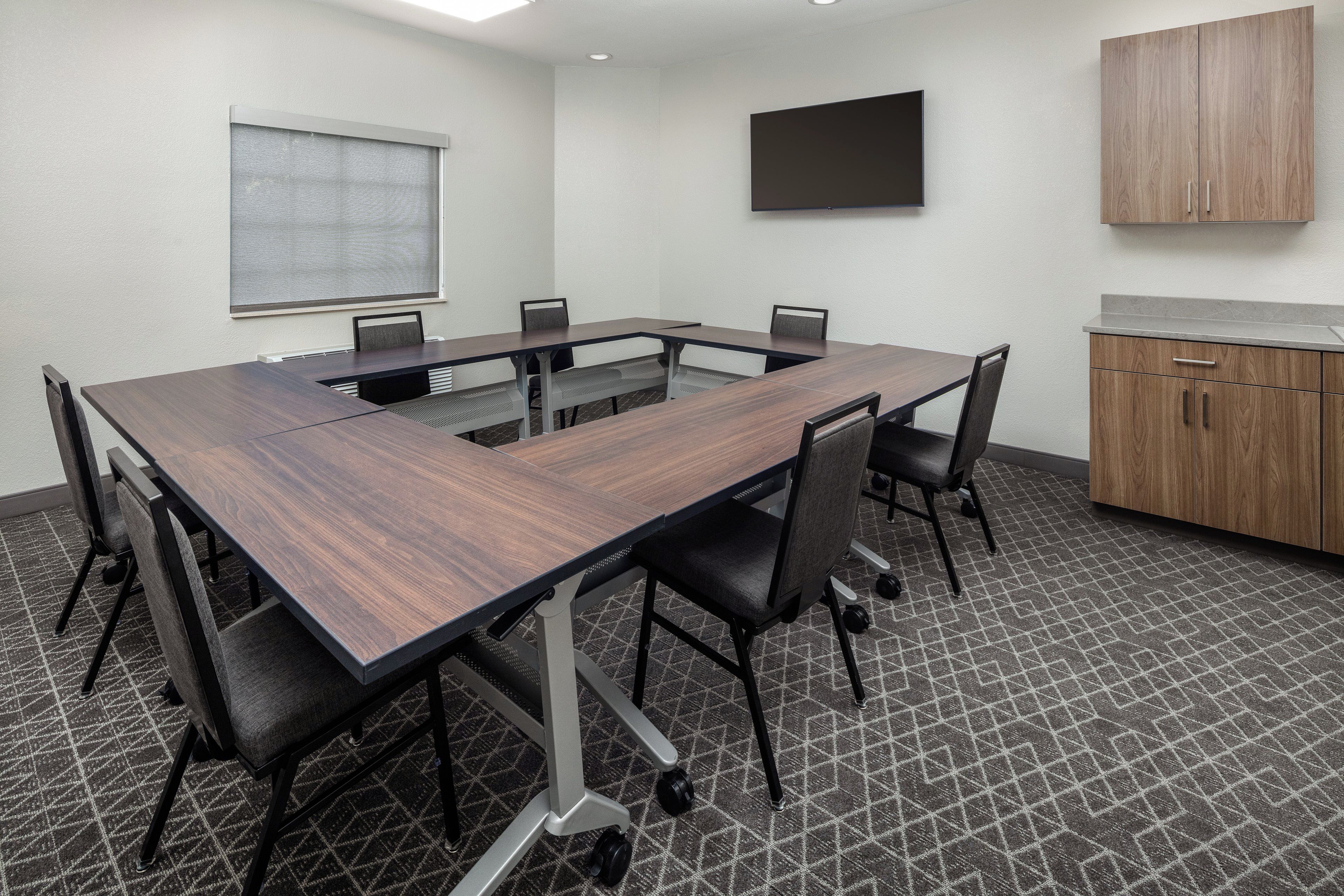 A conference room with a large table, chairs, a television, and a cabinet.