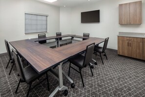 A conference room with a large table, chairs, a television, and a cabinet. - Candlewood Suites St Robert by IHG (St. Robert)