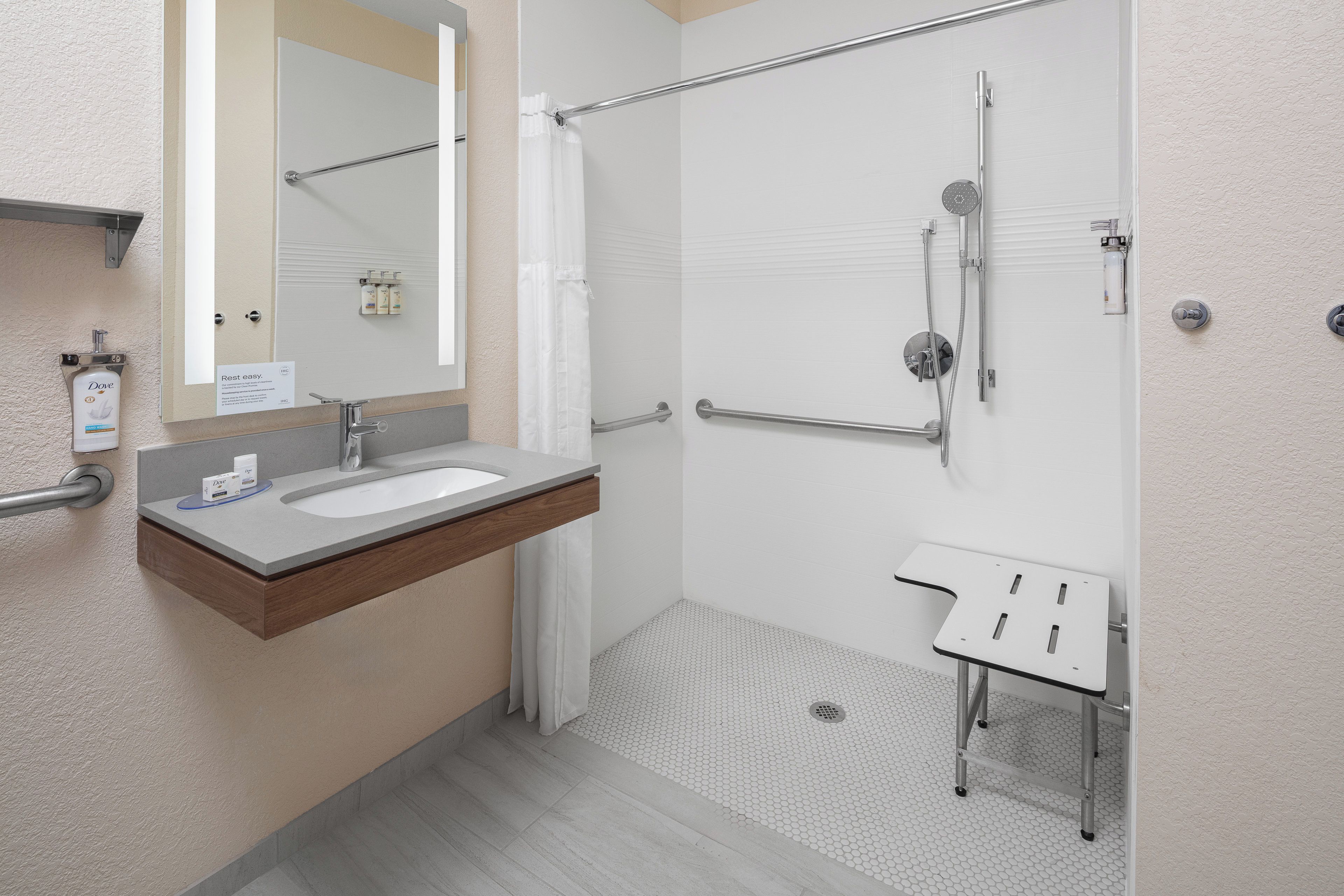 A modern bathroom with a sink, mirror, shower, and a small table.