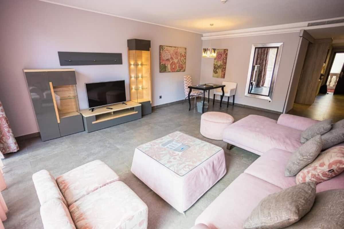 Una sala moderna con un televisor de pantalla plana, un conjunto de sofás, una mesa de centro y una zona de comedor con una mesa y sillas.