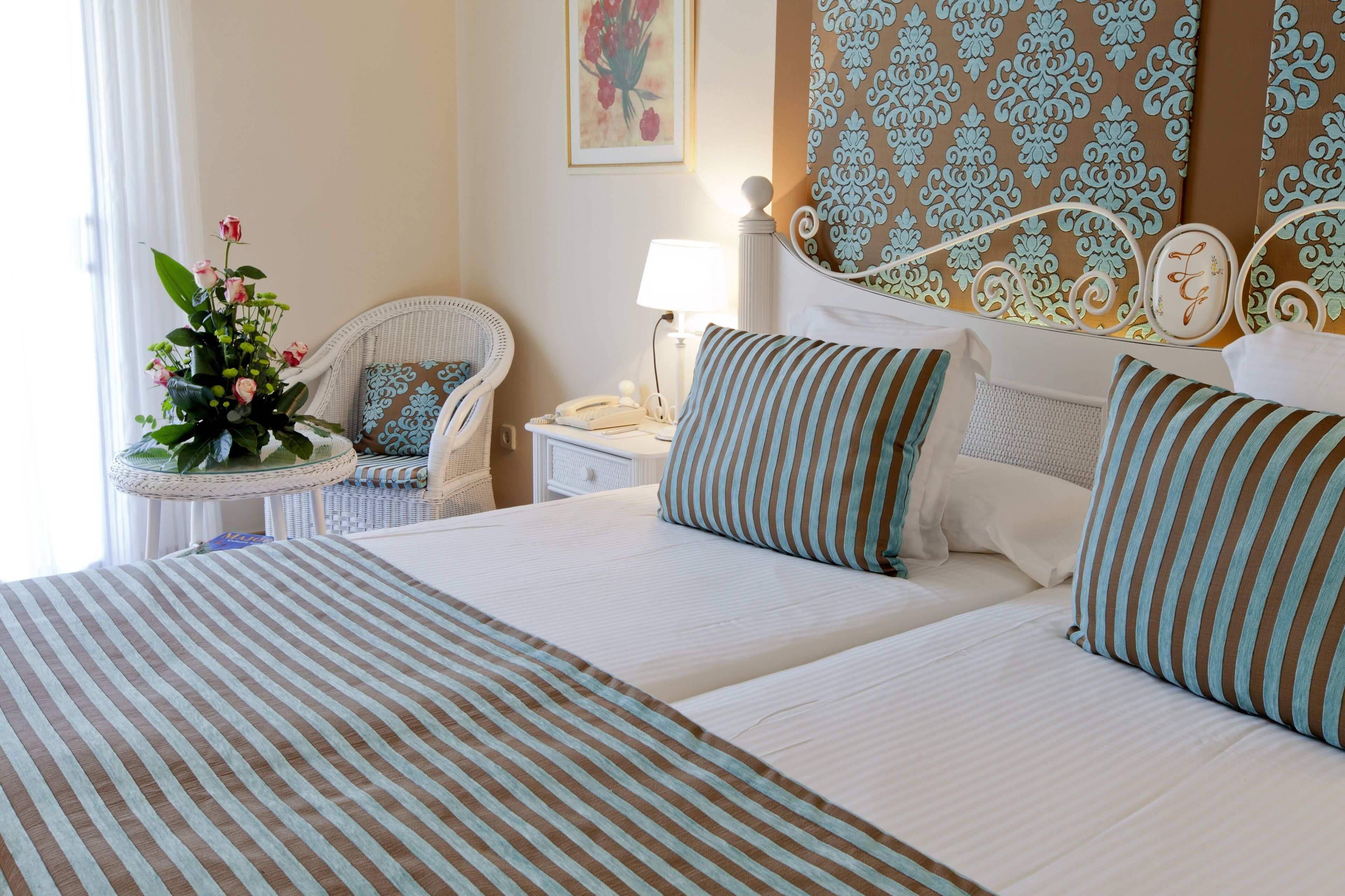 A hotel room with a large bed, a bedside table with a lamp, a chair, and a floral arrangement.