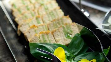 A tray of sandwiches with a sign, a glass of water, and some flowers on a table.