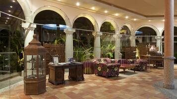 A spacious lobby with a checkered floor, a sofa set, a wooden cabinet, and a decorative lamp.