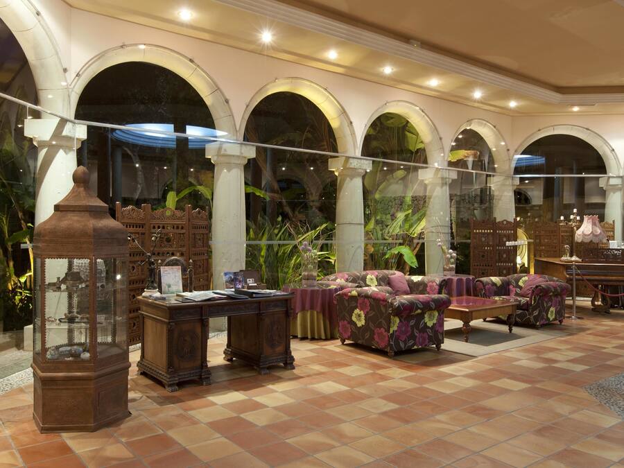 A spacious lobby with a checkered floor, a sofa set, a wooden cabinet, and a decorative lamp.