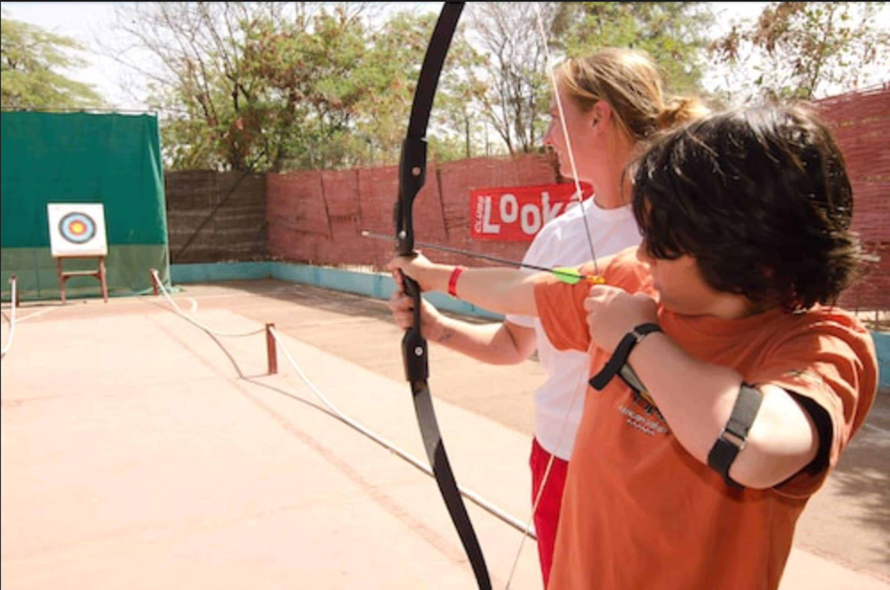 An indoor archery range with a target and a green netted area.