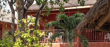 Un hotel con fachada roja, varios balcones y abundante vegetación.