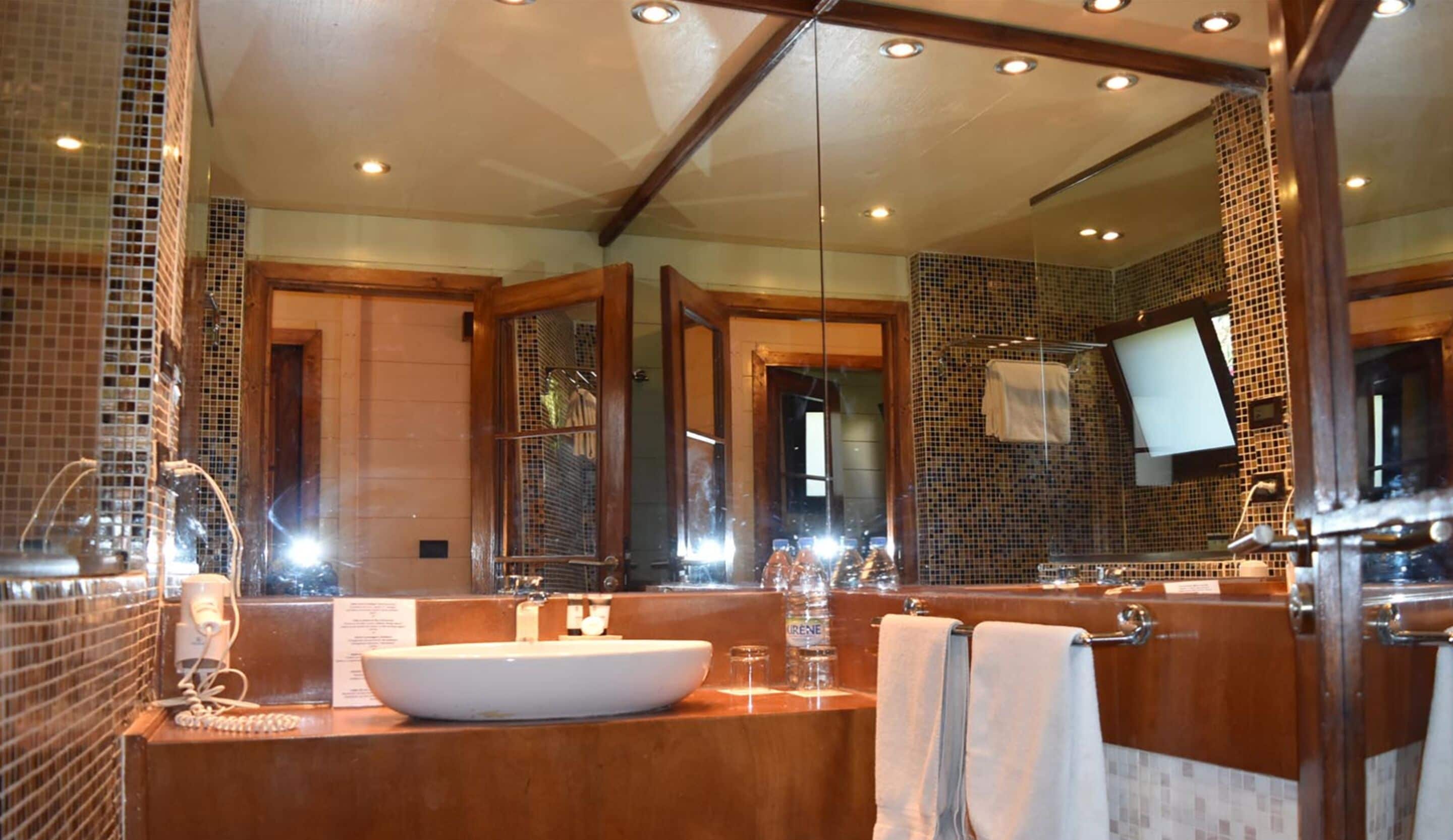 A bathroom with a large mirror, a sink, and a shower area.