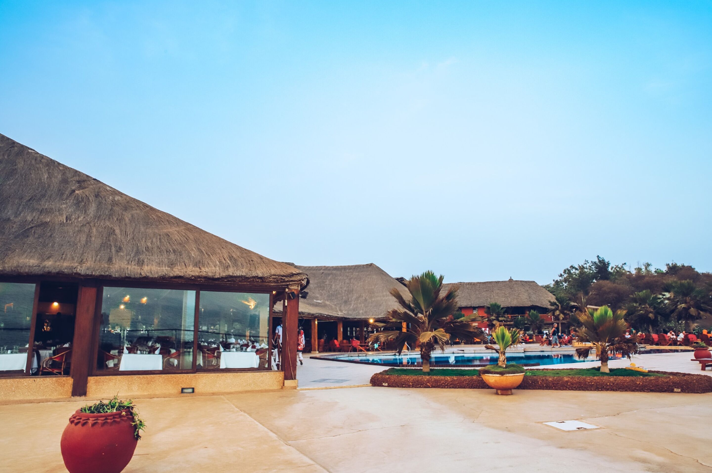 A resort with thatched-roof buildings, a pool area, and outdoor seating.