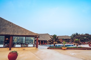 A resort with thatched-roof buildings, a pool area, and outdoor seating. - Royal Horizon Baobab - All inclusive (La Somone)