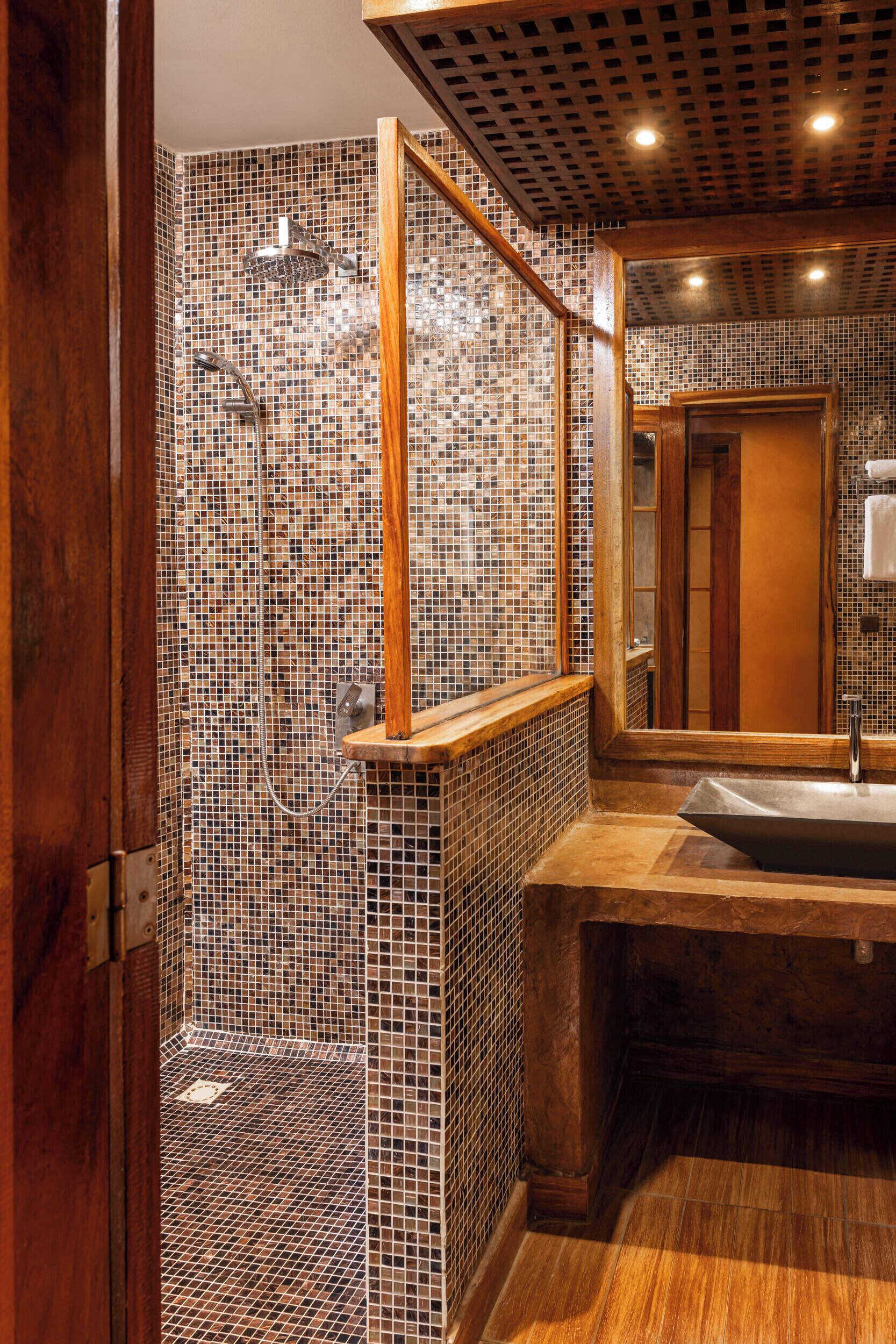 A bathroom with mosaic tile walls, a wooden vanity, and a large mirror.
