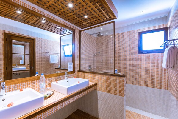A bathroom with two sinks, a shower, and a window.