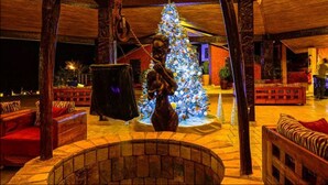 A warmly lit interior with a Christmas tree, wooden furniture, and a stone fireplace. - Royal Horizon Baobab - All inclusive (La Somone)