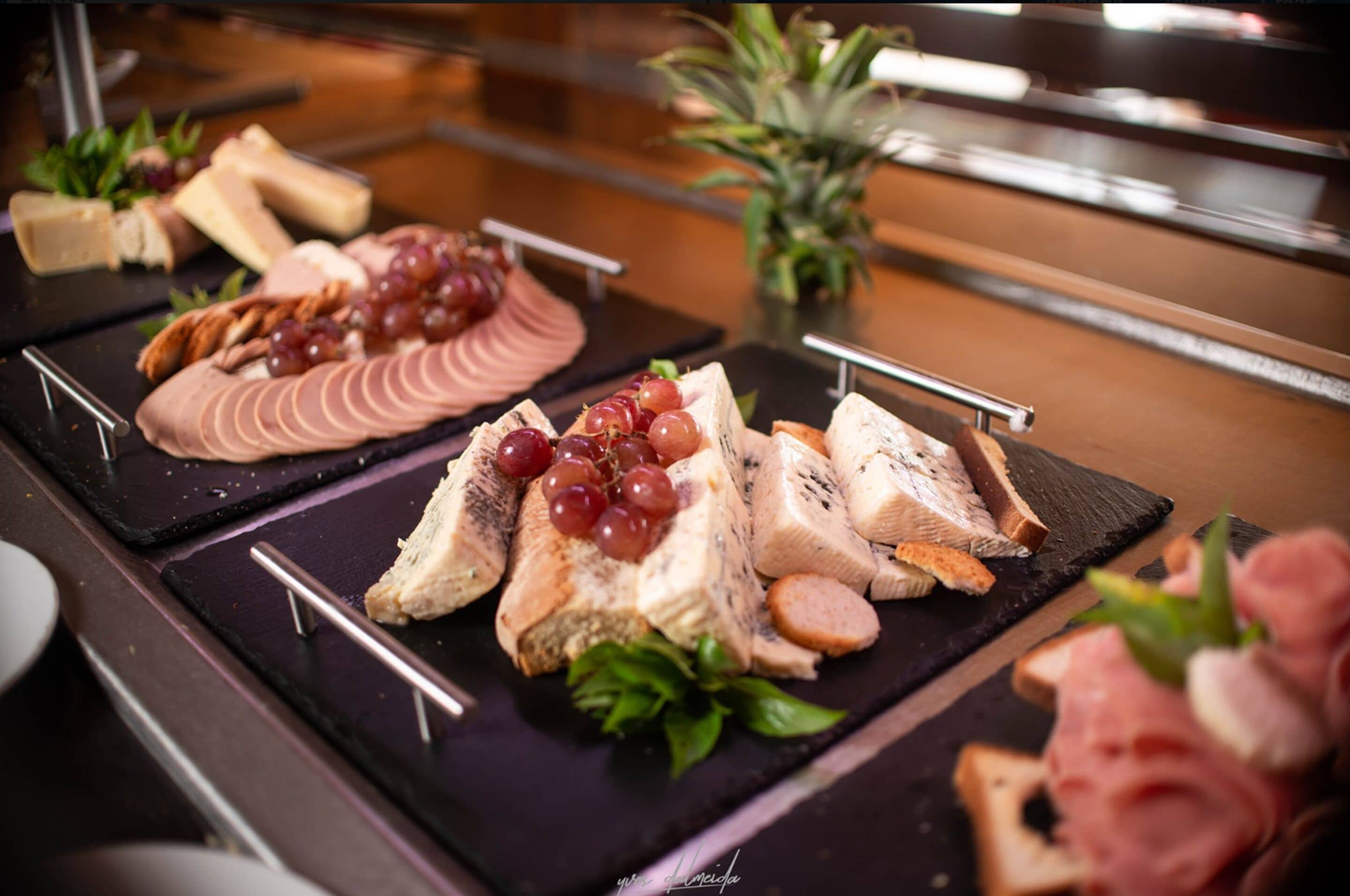 A buffet with various cheeses, fruits, and meats.