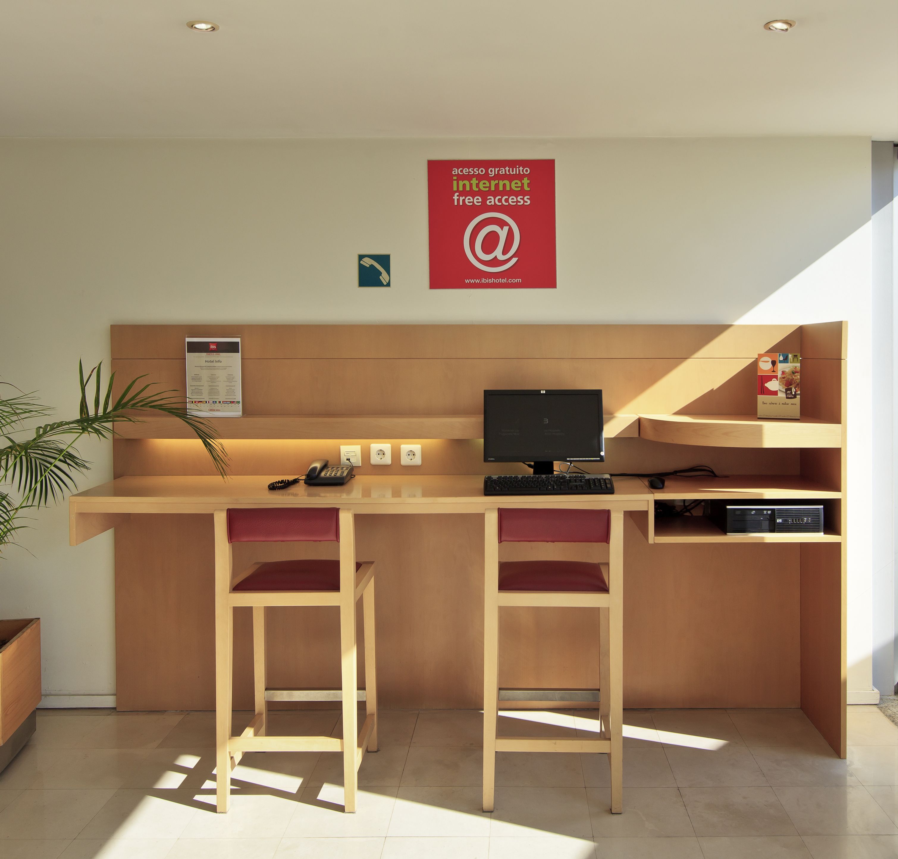 Uma moderna receção de hotel com computador, telefone e aviso a oferecer acesso à internet gratuito.