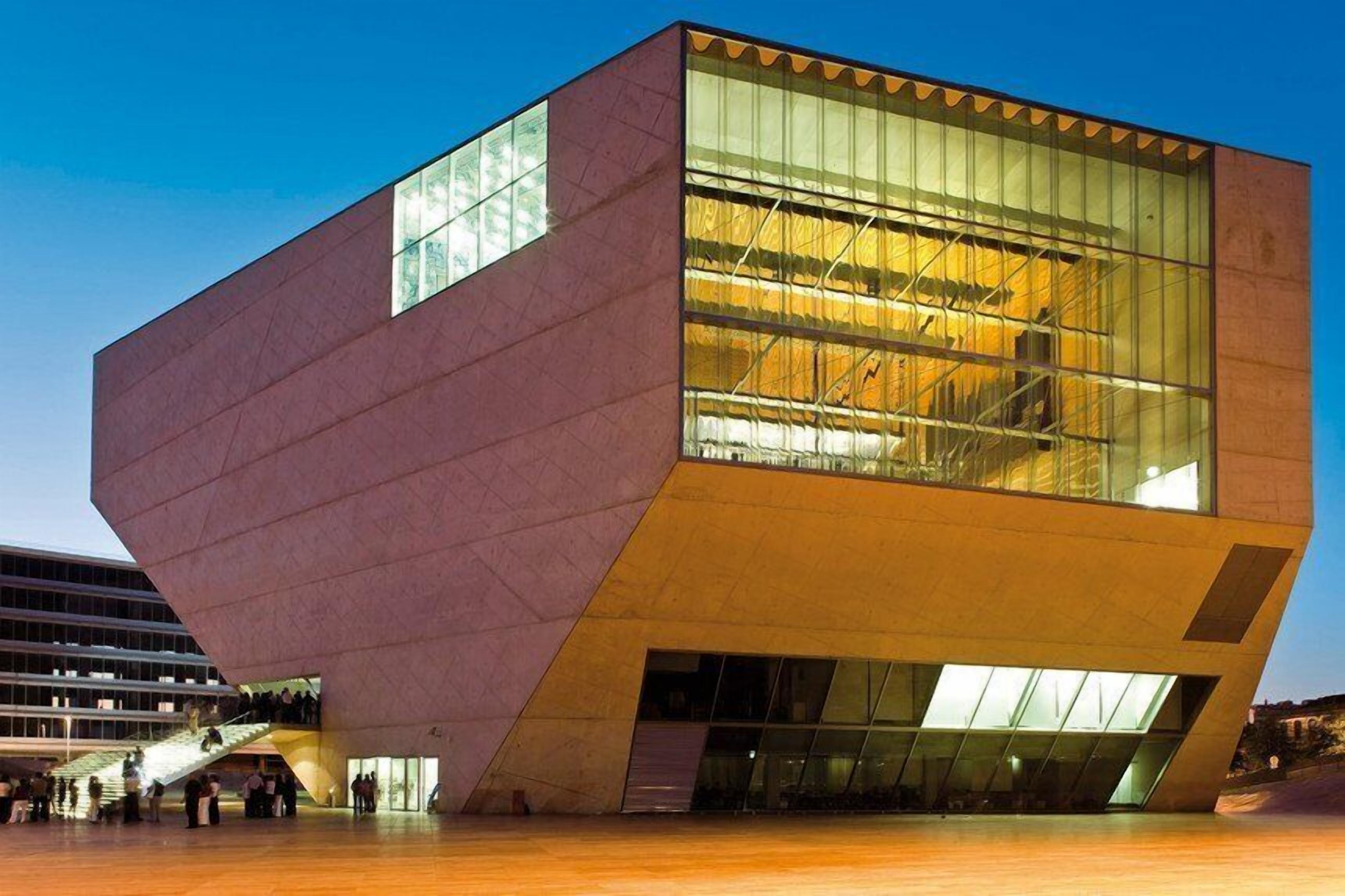 Un edifici modern amb un disseny angular singular, grans finestres de vidre i una àrea exterior àmplia.