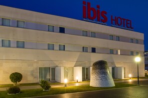 A modern hotel building with a prominent "ibis HOTEL" sign.