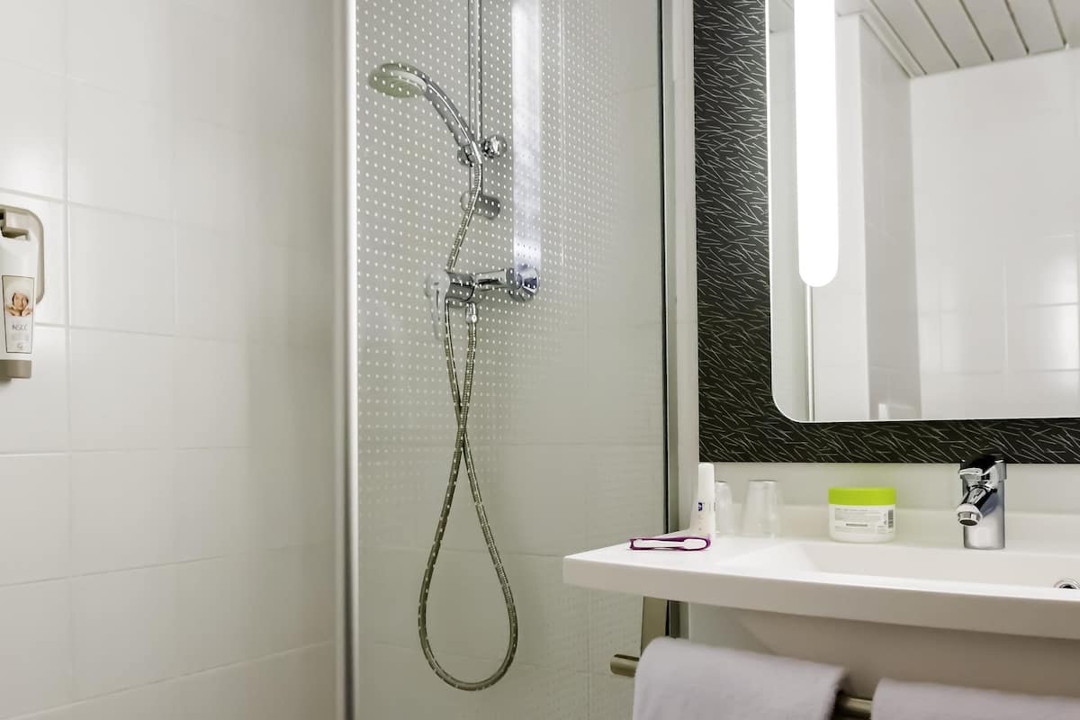 Une salle de bain moderne avec une douche à parois de verre, un lavabo blanc avec un miroir et un porte-serviettes.