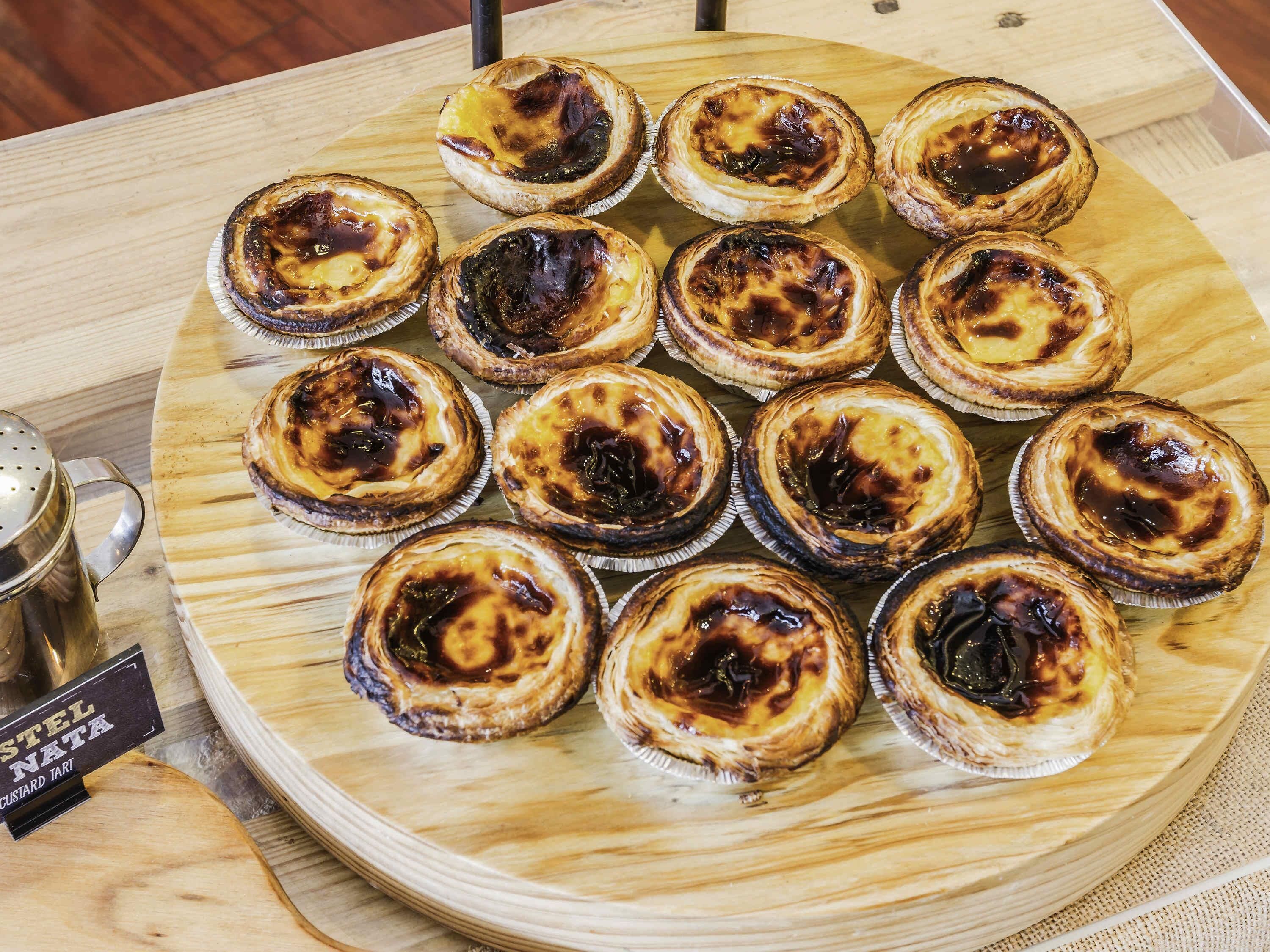 A wooden table with a plate of custard tarts.