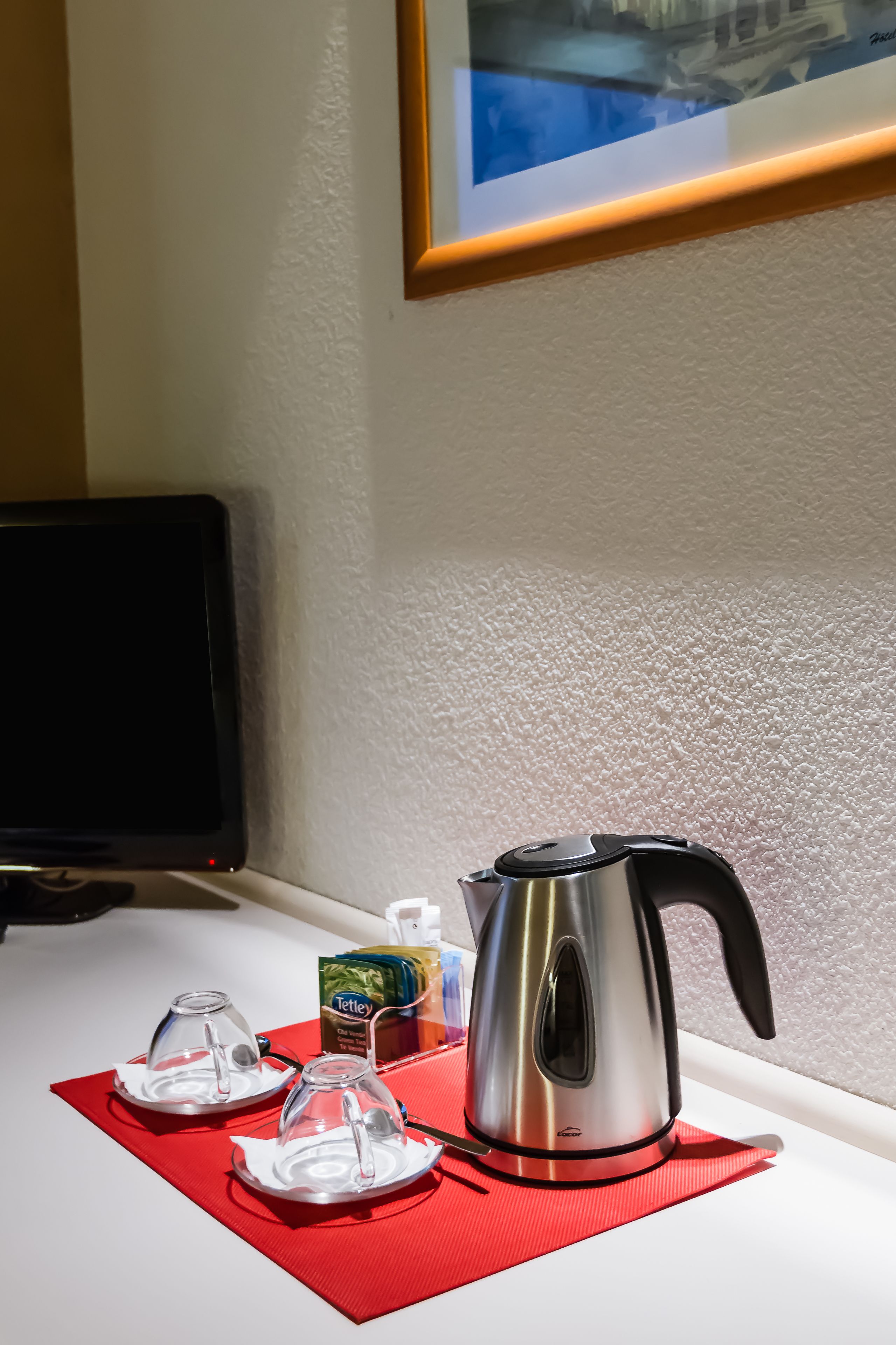 Un comptoir de cuisine avec une bouilloire, deux carafes en verre et une boîte de sachets de thé.