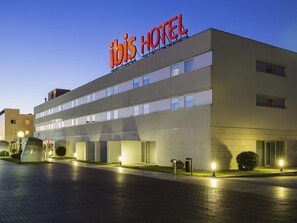 A modern hotel with a prominent sign, multiple floors, and a well-lit entrance. - ibis Porto Sao Joao (Porto)