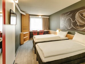 Habitación de hotel con dos camas, un escritorio, dos sillas, un armario y un cuadro abstracto grande en la pared.