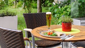 A round table with a plate of food, a glass of beer, and a potted plant. - ibis Wien City (Vienna)