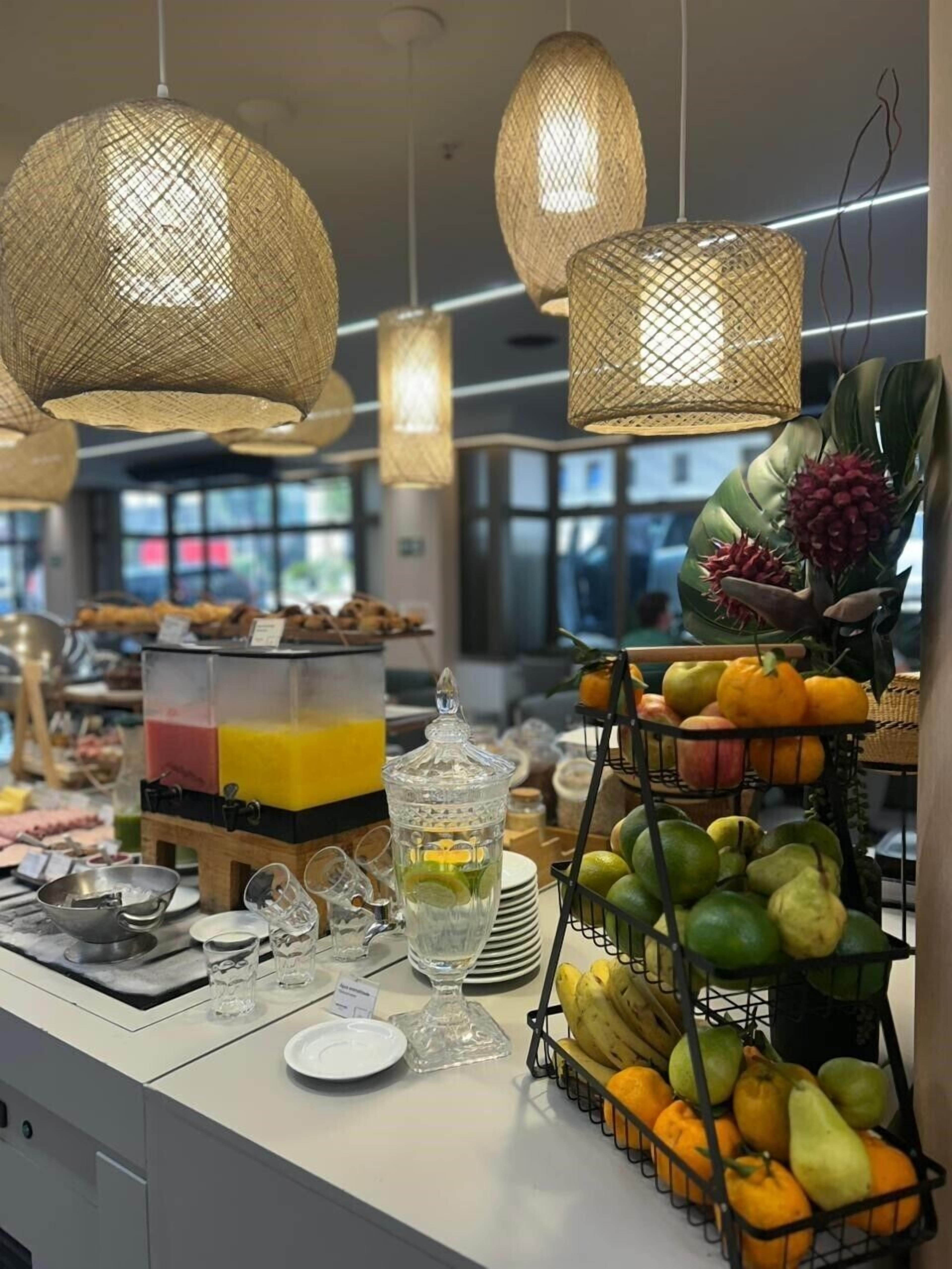 Een ontbijtbuffet met verschillende soorten fruit, een jusdispenser en een assortiment dranken.