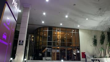 Ein Hotel mit Glasfassade, Treppen zum Eingang und einer Beschilderung für Restaurant und Parkplatz.