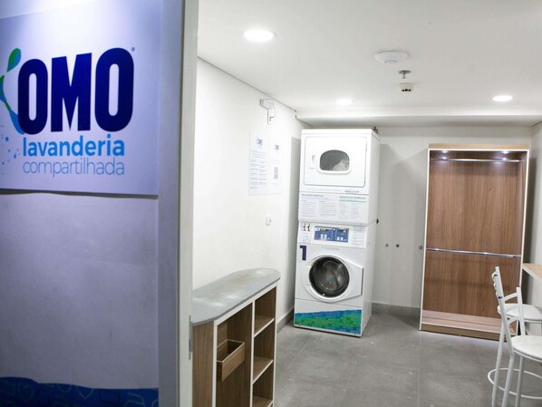 A laundry room with a washing machine, a dryer, and a wooden door.