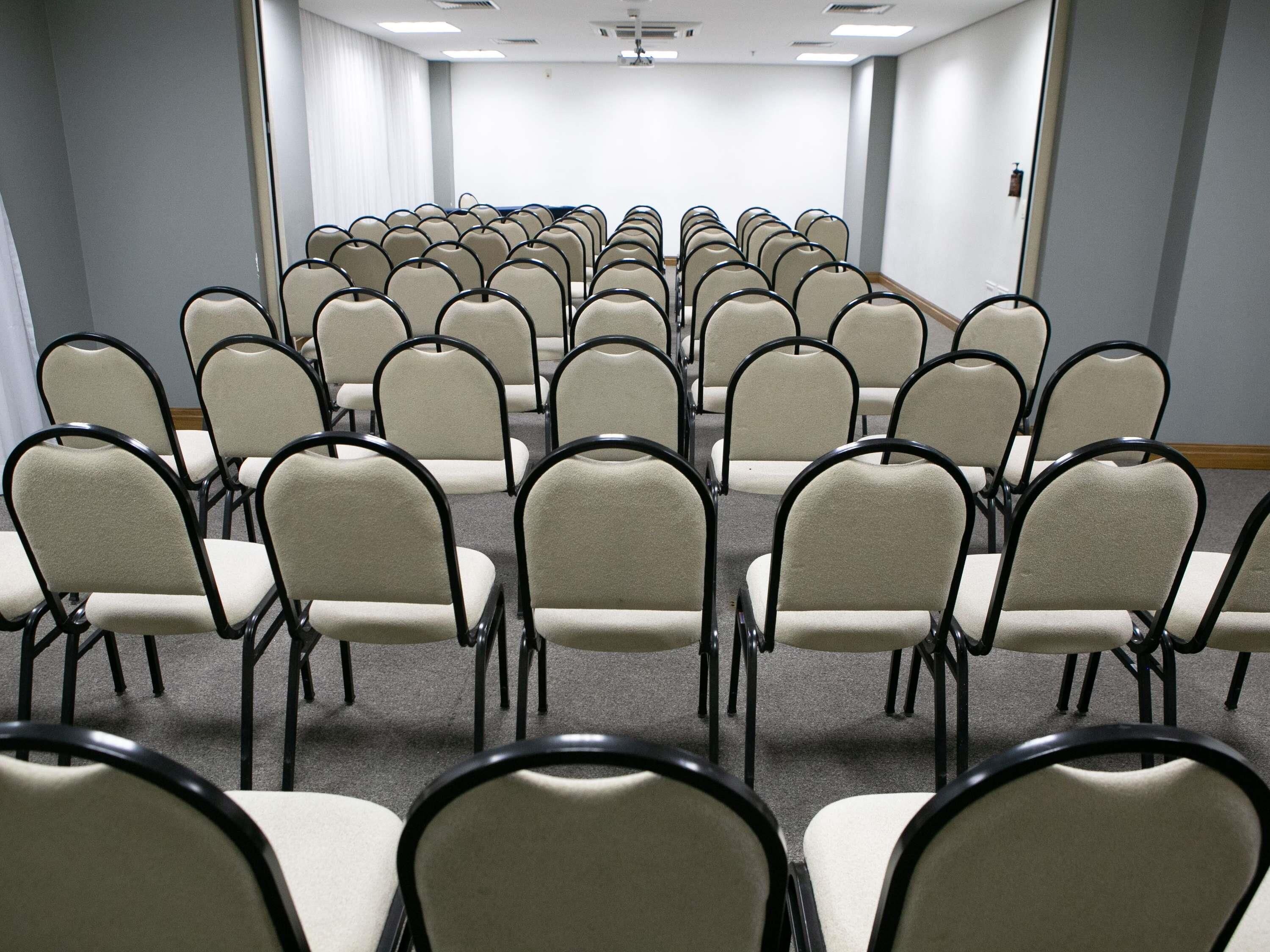 A conference room with rows of chairs and a carpeted floor.
