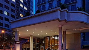 Entrada de hotel con vestíbulo techado, amplias columnas y un cartel que dice 'Mercure'.